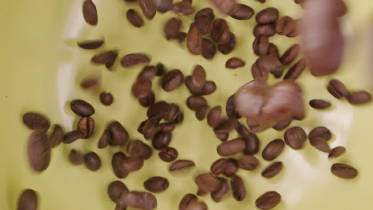 Molti chicchi di caffè che cadono su una superficie verde e rimbalzano.
