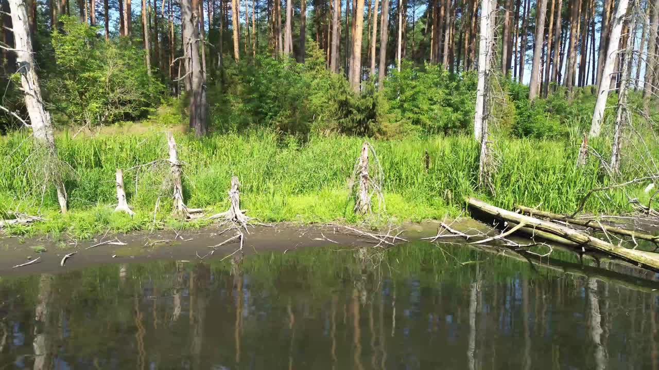 Dron unosi się nad europejskim jeziorem oświetlonym świtem, uchwycając spokojną lagunę, bujny las i elegancki most — hipnotyzujący widok z lotu ptaka z urzekającymi ujęciami z nieba