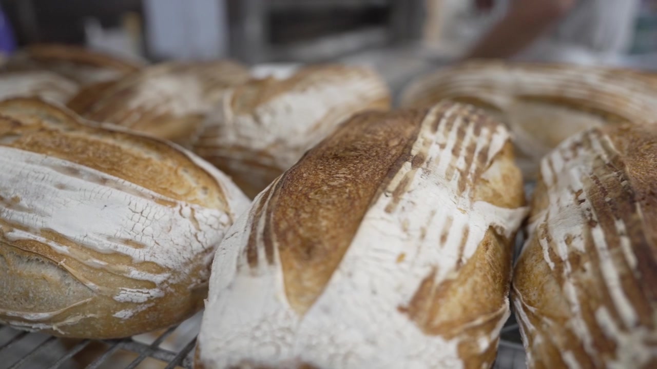 A woman rolling dough in a private bakery, captured in 4K resolution at 60fps, slow motion.