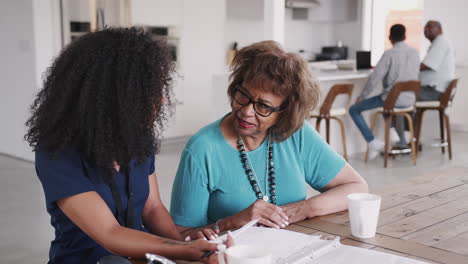 Healthcare-worker-filling-in-a-form-with-a-senior-patient-during-a-home-health-visit,-elevated-view