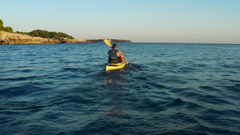 man in vest kayaking on a wavy ocean near city of pula in croatia’s istrian peninsula