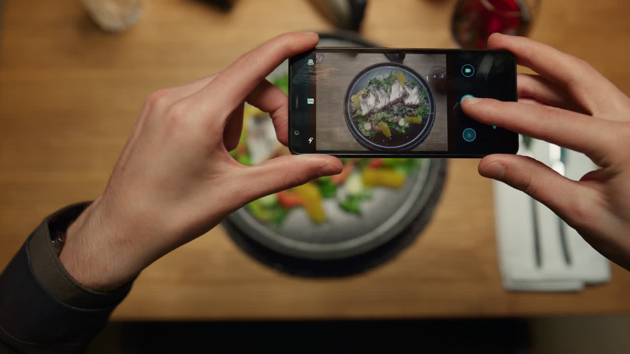 hombre tomando fotos de la cena usando el teléfono en la mesa del restaurante. disfruta del concepto de la comida.