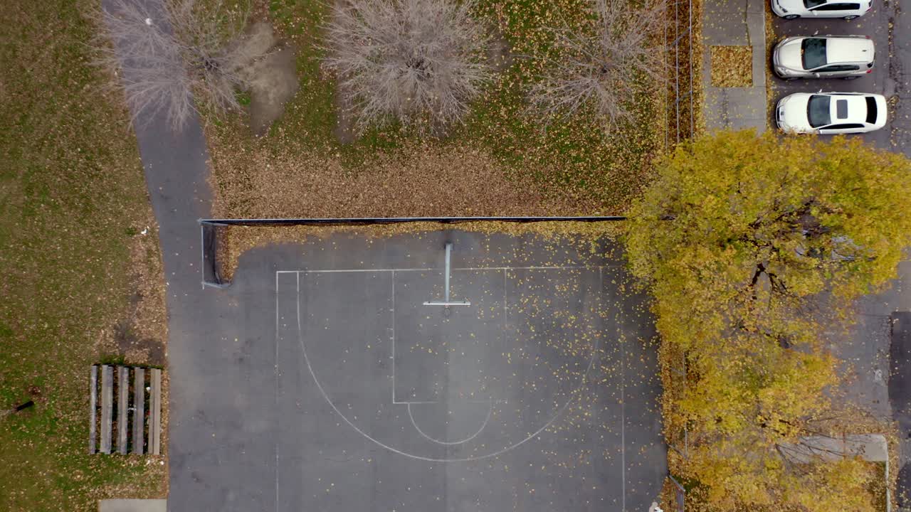 drone descendiendo sobre un aro de baloncesto sobre una cancha en un parque público