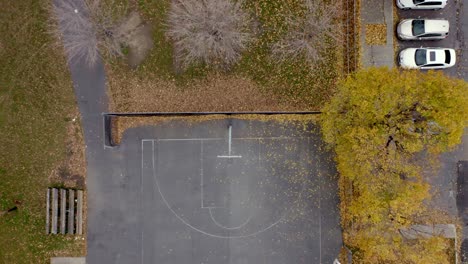 drone descending on a basketball hoop over a court in a public park