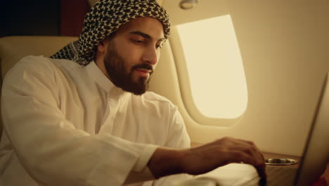 Smiling businessman typing laptop on jet closeup. Successful man work computer