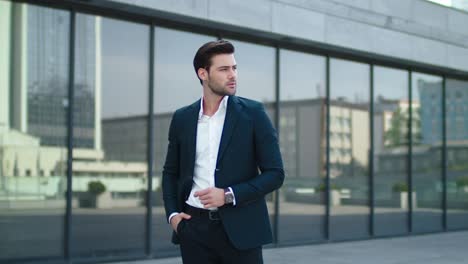 closeup businessman standing near building at street. man putting hand in pocket