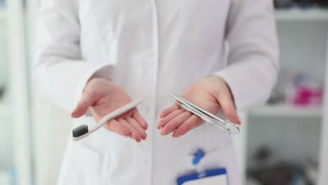 A dental professional holding a toothbrush and dental tools