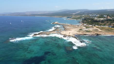 Agios-georgios-beach-in-cyprus-with-clear-turquoise-waters-and-sailboats,-aerial-view