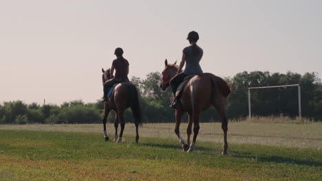 two women riding horses in a field