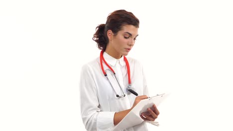 Friendly-young-female-doctor-reviews-and-writes-notes-on-a-clipboard.-Portrait-of-young-medical-professional-with-stethoscope-and-lab-coat-isolated-on-white-background