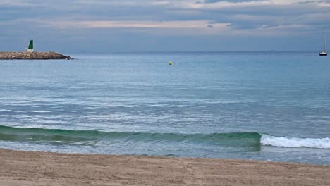 A-sailboat-on-the-horizon-in-the-port-of-El-Campello,-Spain-on-a-cloudy-day