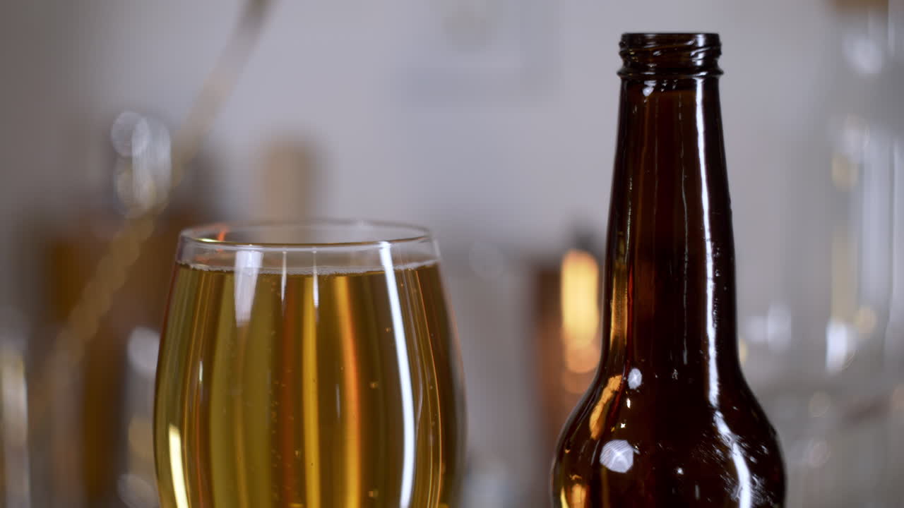 Birra dorata in un bicchiere da birra artigianale con bollicine e una bottiglia di birra accanto, primo piano