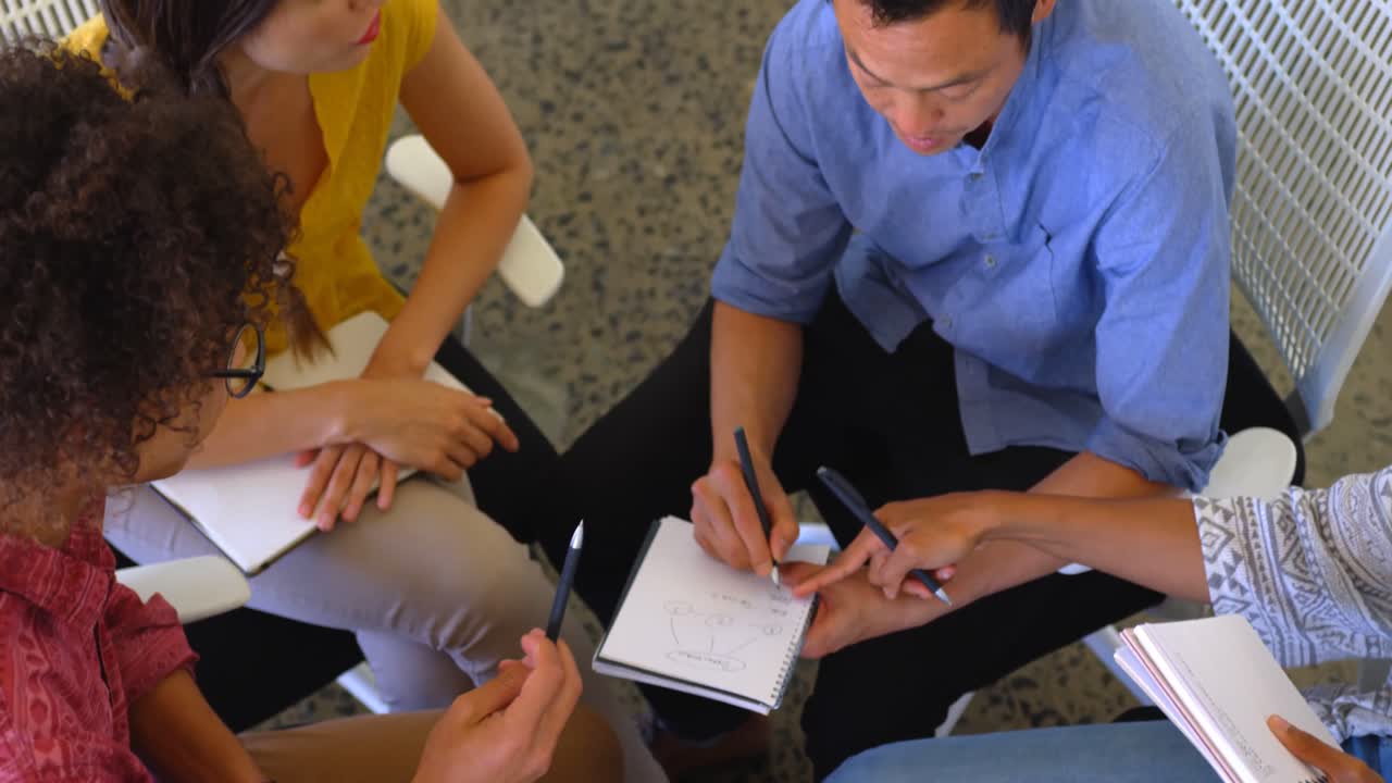 Multi-ethnic business colleagues writing on a diary in modern office 4k