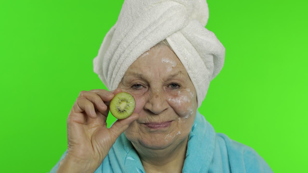 abuela anciana en bata de baño. anciana con la mitad de kiwi en la mano