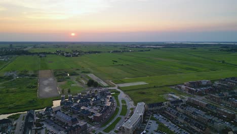 Aerial view of modern residential area of Vathoorst nestled amidst vast, lush green fields in Amersfoort, Netherlands, at sunset