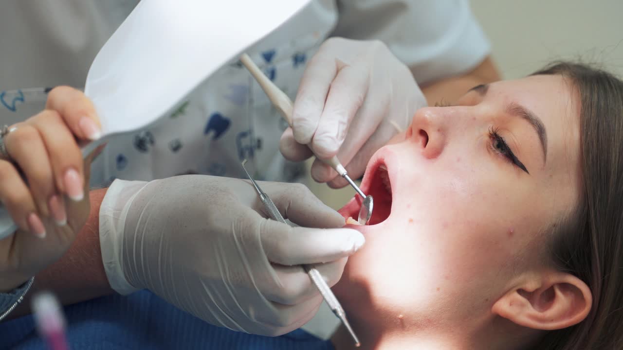 The girl at the dentist office shows sick teeth while looking in the mirror