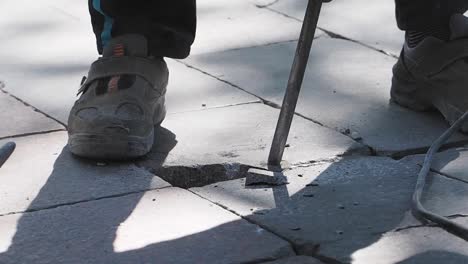 worker using jackhammer to break paving stones