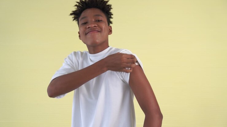African American teenager showing COVID-19 vaccine bandage merrily