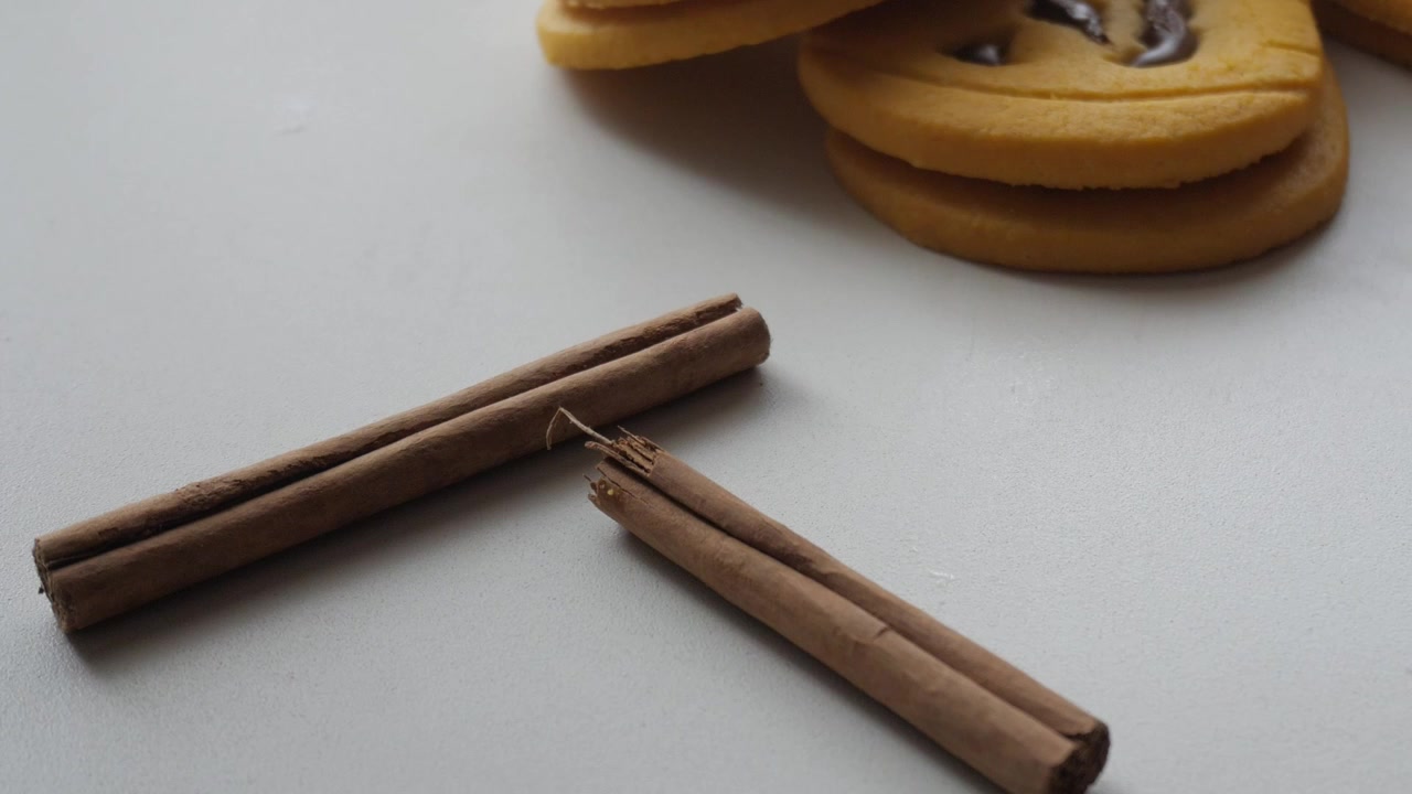 Zoom out de biscoitos de Halloween, em formato de abóboras com rosto de chocolate, fundo branco, espaço para texto, canela como decoração.