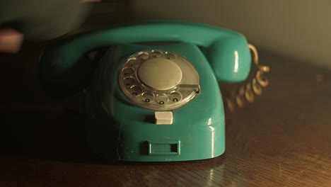 a hand in a coat puts an old analog corded telephone on the secretary