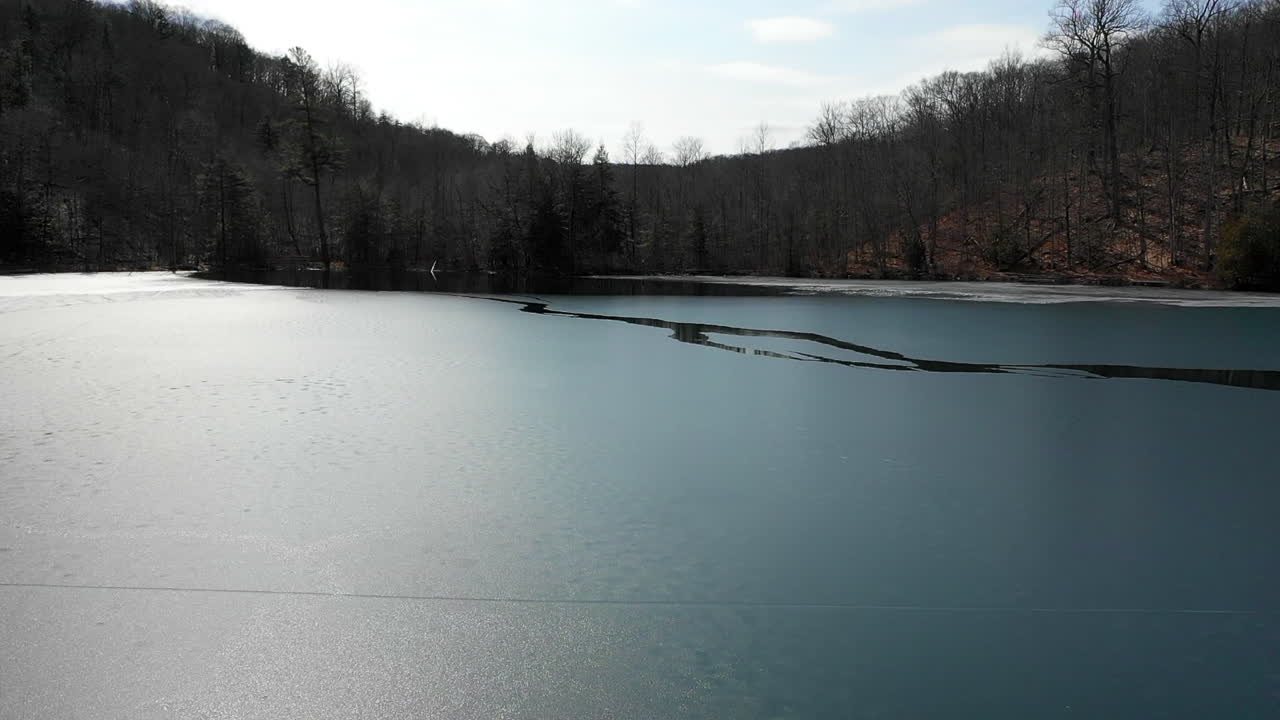 Drone flys very fast over icy blue green lake state park new york