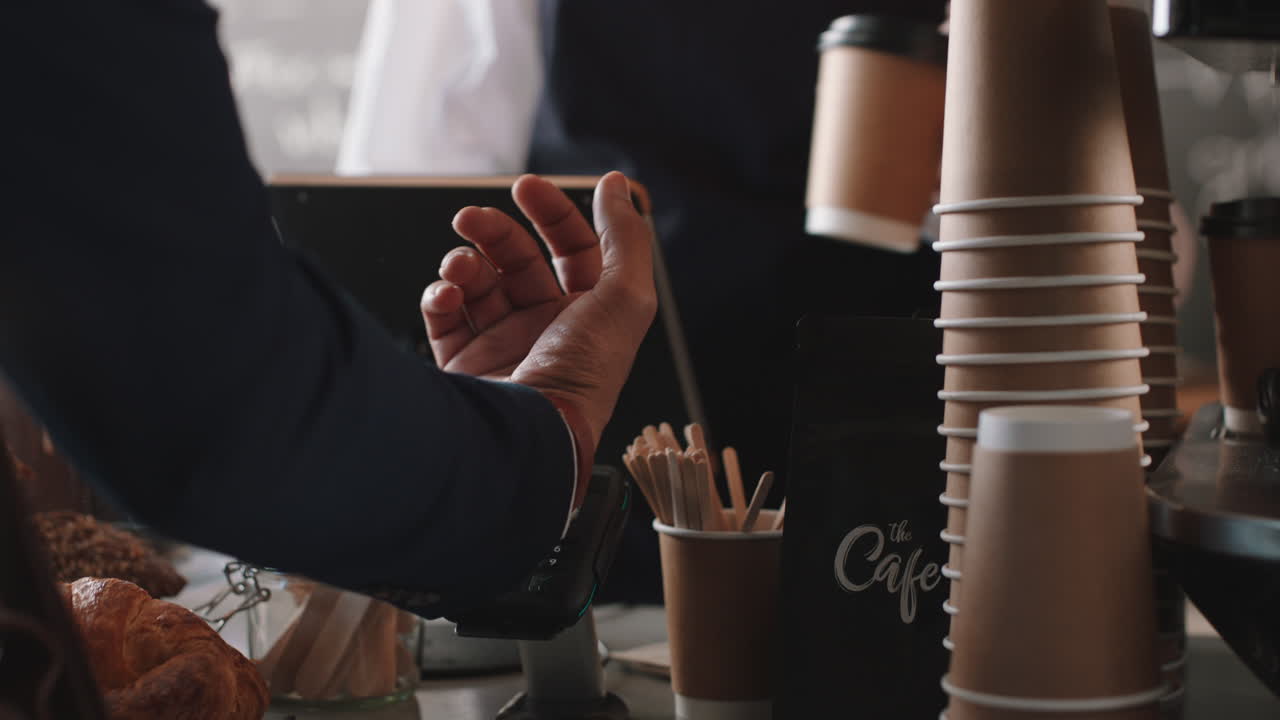 행복 한 바리스타 여성 이 고객 을 섬기고 스마트 시계 를 사용 하여 지불 하고 커피 를 사서 카페 에서 돈 을 쓰고 있다