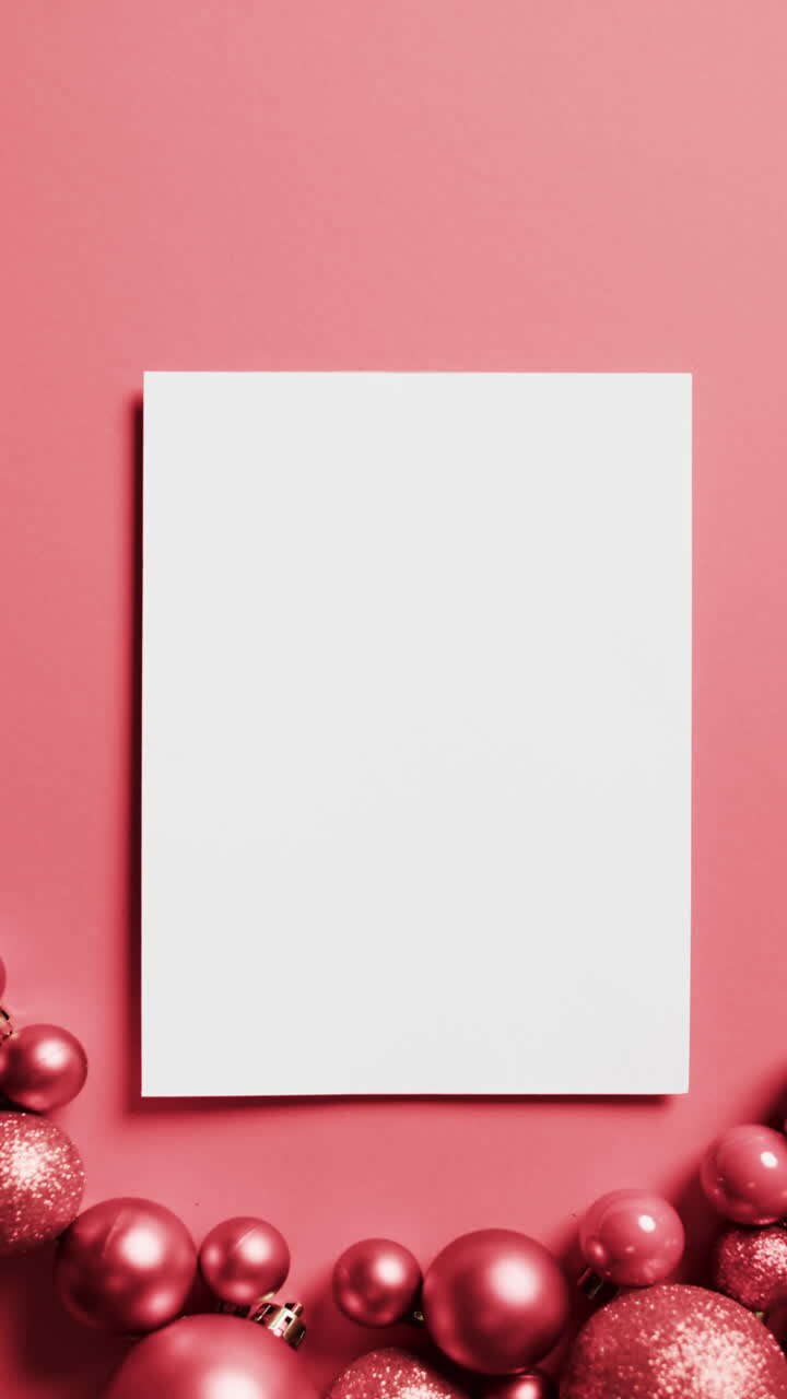 Vertical video of red baubles christmas decorations, white card with copy space on red background