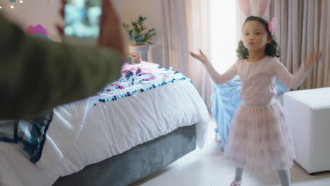 niña feliz jugando a disfrazarse con orejas de conejo en el dormitorio con su madre tomando fotos usando un teléfono inteligente compartiendo en las redes sociales