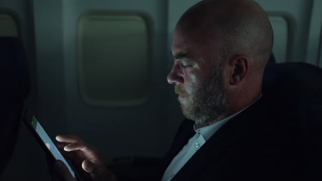 a man working on a tablet pc on a night flight on an airliner airplane