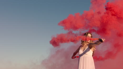 Mujer-Bailando-Con-Una-Bomba-De-Humo-Rosa-En-La-Playa-Al-Amanecer-Celebrando-La-Libertad-Creativa-Con-Un-Baile-Juguetón-En-Cámara-Lenta