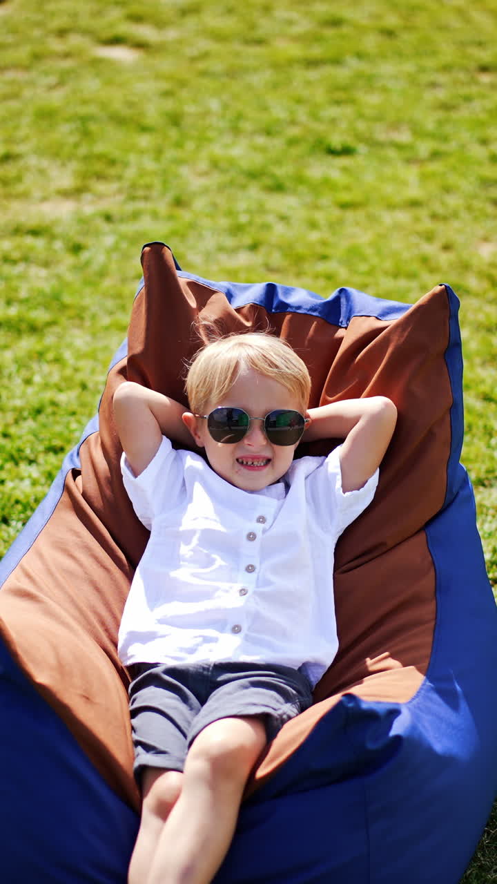 Young little child in the garden. Cheerful cute boy having fun outdoor. Vertical video