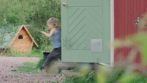 young kid bolts out of wooden house back door in countryside, profile tracking