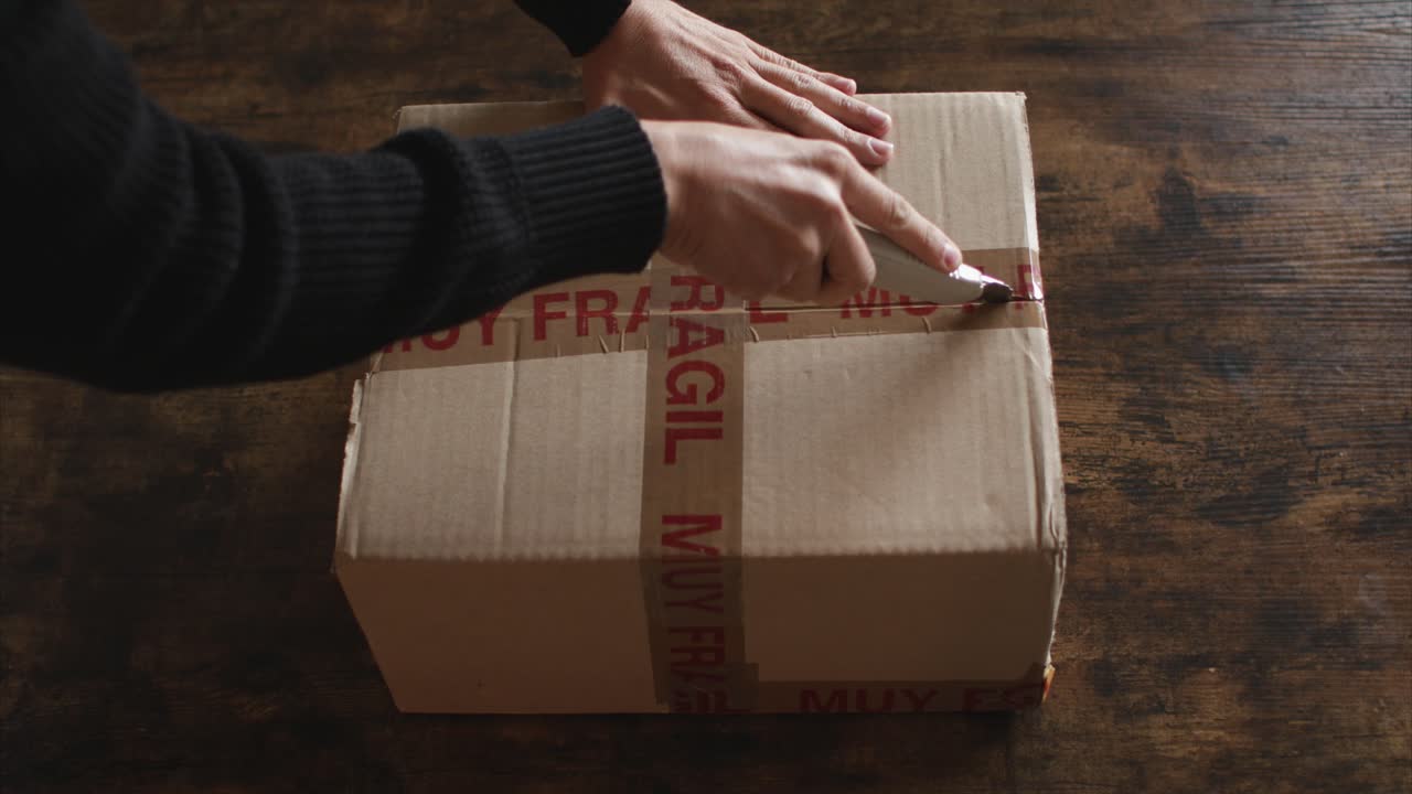 un hombre abriendo una caja con una navaja