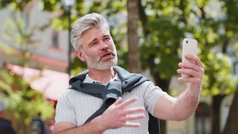 mature man blogger use smartphone communicating video call online with subscribers recording stories