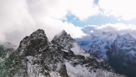 aerial view of the snow-capped valmalenco alps in italy, beautifully framed by clouds and blue sky. the majestic peaks convey a sense of tranquility and awe. parallax shot