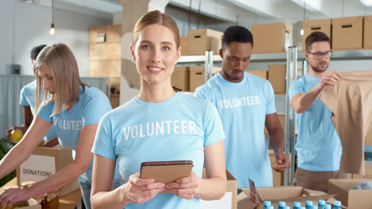 Caucasian female volunteer typing on tablet and smiling at camera