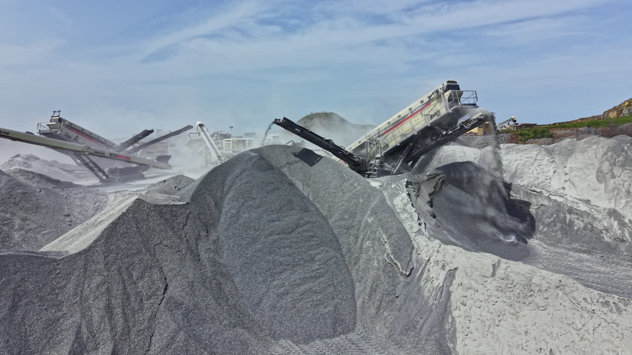 Granite quarrying process with machinery and stone piles under a clear sky in a working landscape