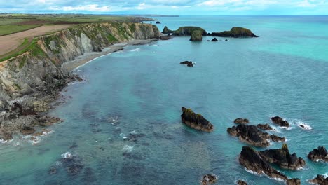 drone establishing shot of sheltered bay with crystal clear water coastline of waterford ireland