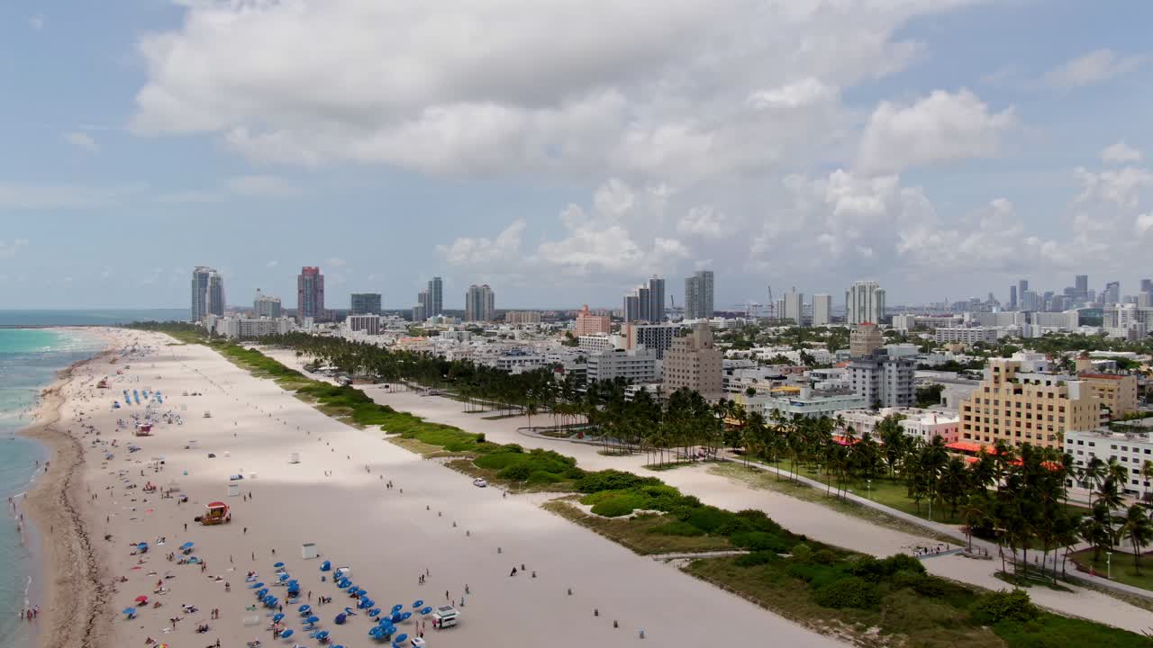 Spiaggia tropicale sabbiosa e skyline di Miami, drone aereo in avanti
