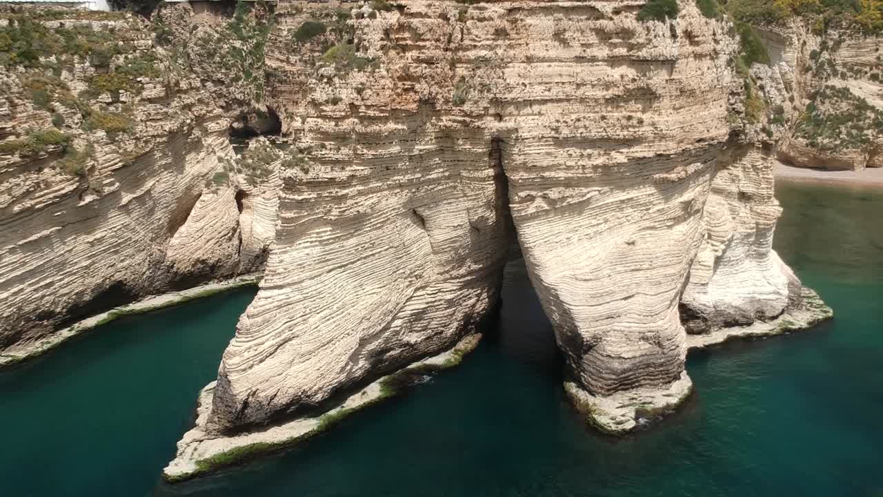 disparo de grúa que se levanta revelando el hermoso paisaje urbano de beirut detrás de enormes rocas de paloma rawshe, líbano