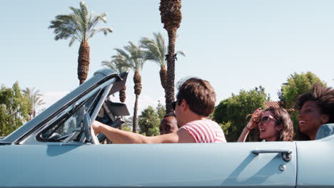 Young-adult-friends-on-the-road-in-a-convertible,-low-angle