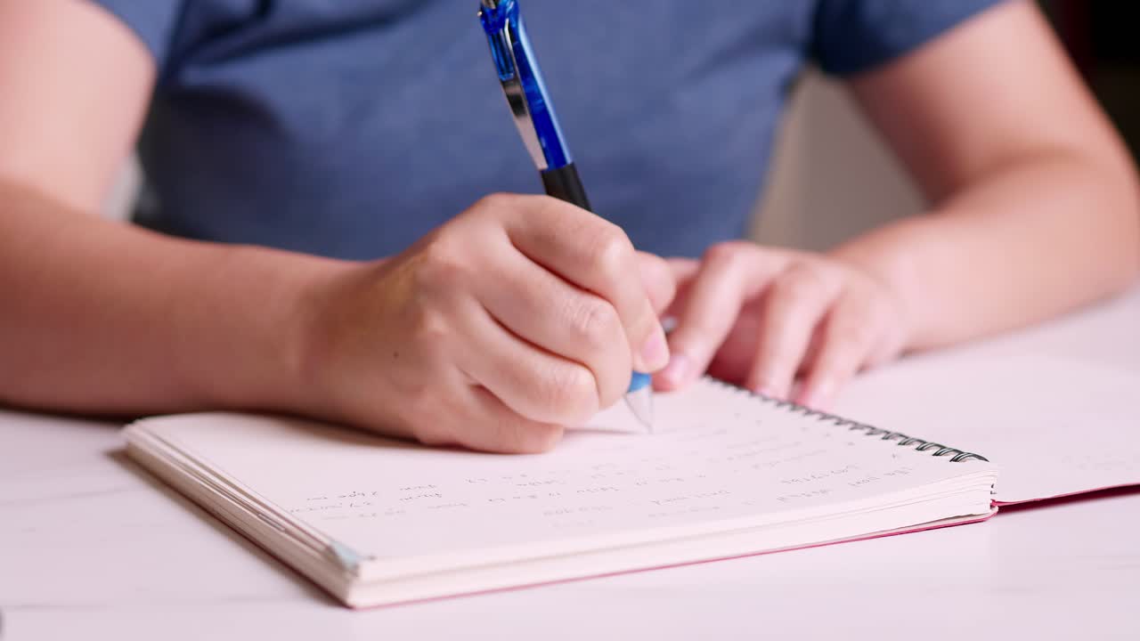 manos cercanas tomando notas en un cuaderno sobre la contabilidad de cada mes en casa