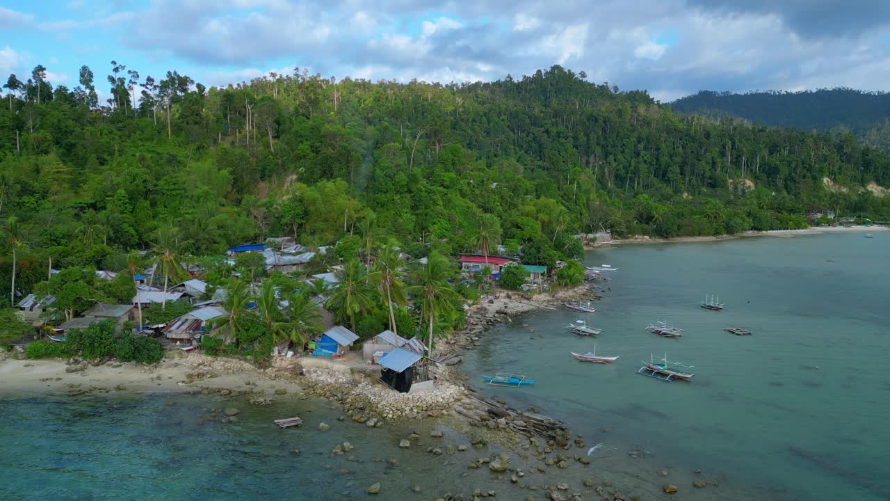 Villaggio di Port Barton, Palawan, Filippine, con barche tradizionali che riposano su acque cristalline turchesi accanto a una spiaggia sabbiosa. Vista aerea mozzafiato, panorama statico da drone in hovering.