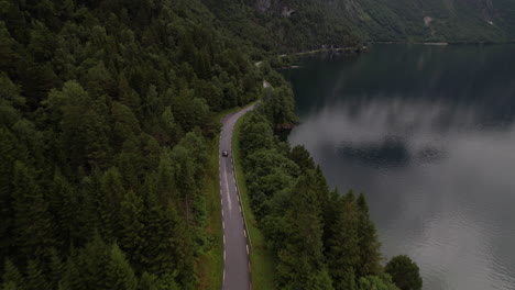 car driving along lakeside road next to eikesdalsvatnet lake in norway, aerial view