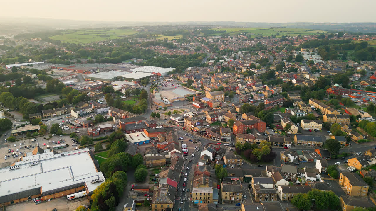 un avión no tripulado registra heckmondwike, reino unido, con edificios industriales, calles bulliciosas y el centro antiguo de la ciudad en una noche de verano