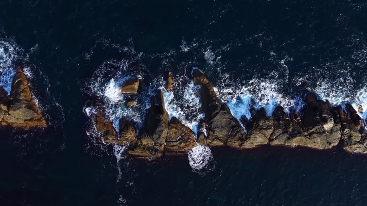 Stunning ocean waves crashing against rugged rocks at sunset, revealing the dynamic beauty of nature's coastline