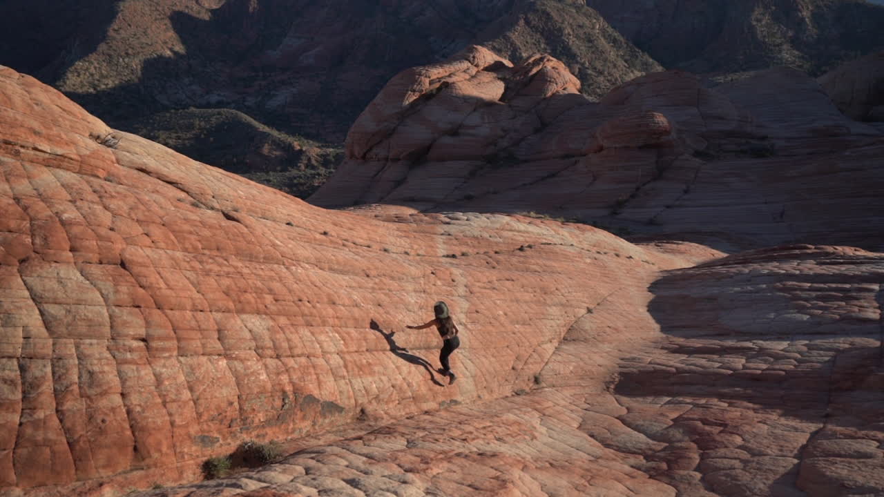 espalda de una mujer joven caminando en formaciones rocosas en yant flat candy cliffs senderismo, utah ee.uu.