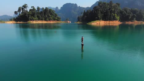 un hombre parado en un tocón de madera, a punto de saltar al agua turquesa de tailandia - antena