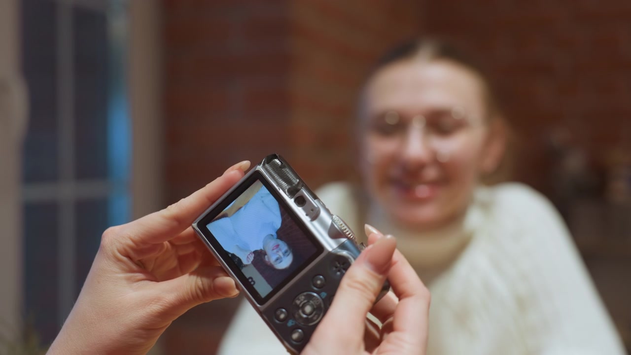 Manos sosteniendo una cámara digital, capturando y revisando fotos de una mujer.