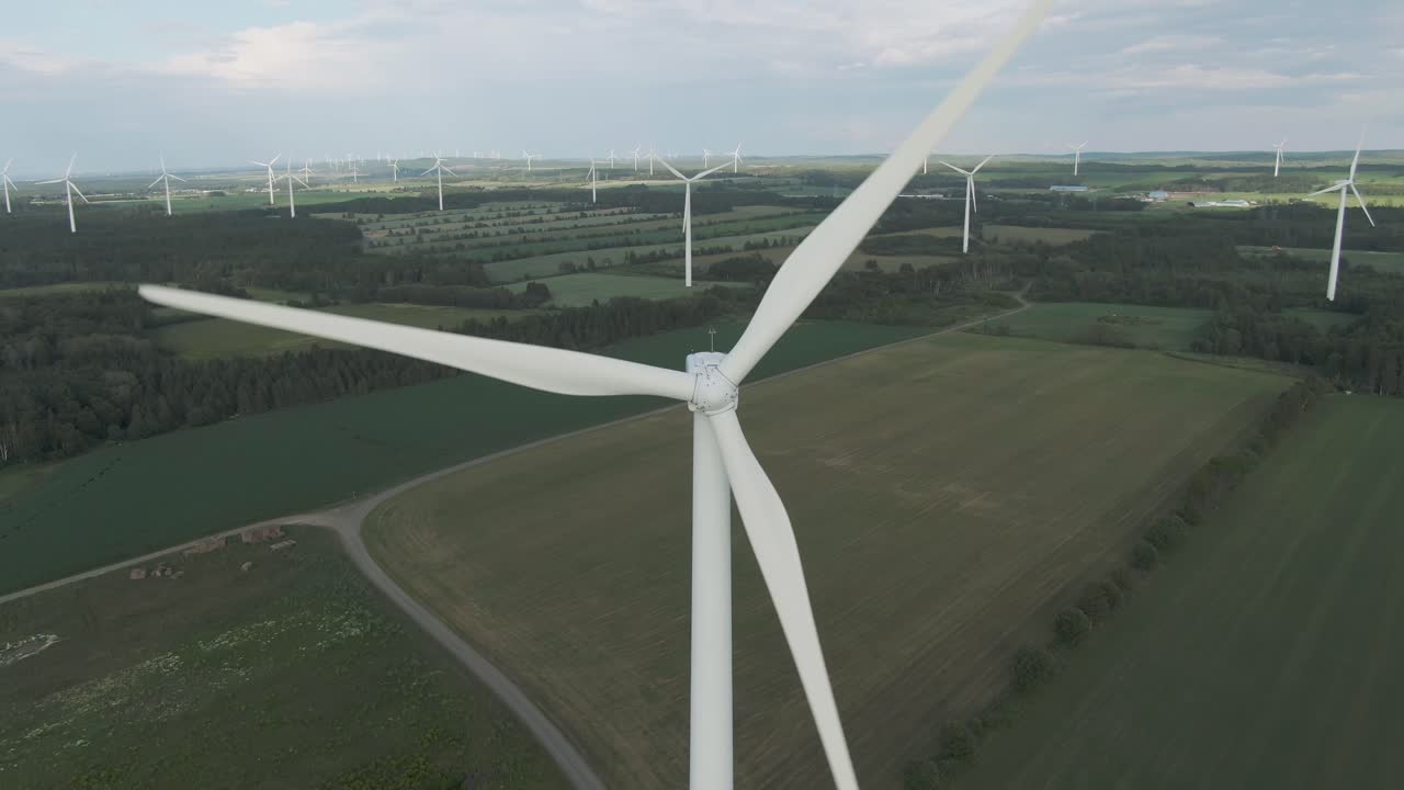 Wind Turbines Converting Electrical Energy From The Lush Green Fields During Summer In Northern Quebec, Canada. - aerial drone shot